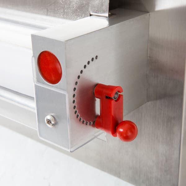 A red button on the metal Estella dough sheeter.