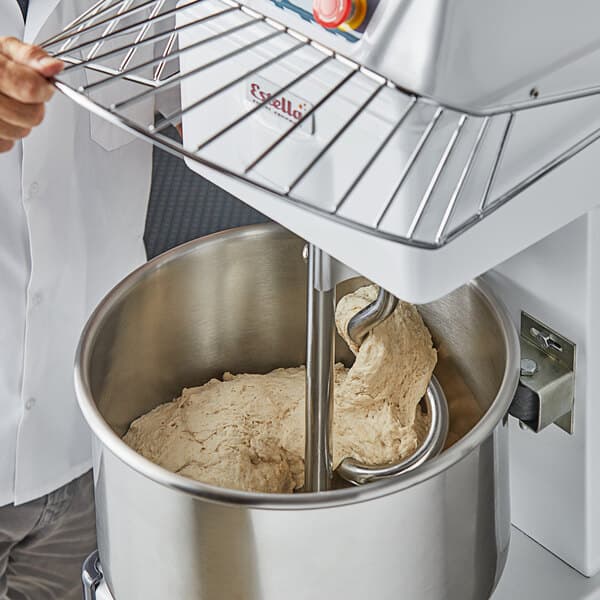 a person holding a metal rack with dough in a bowl