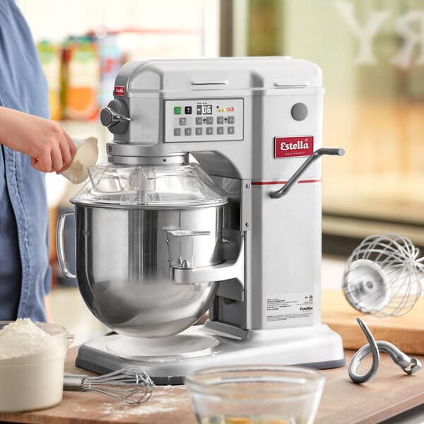 A woman using an Estella commercial mixer to mix cake batter in a white bowl.