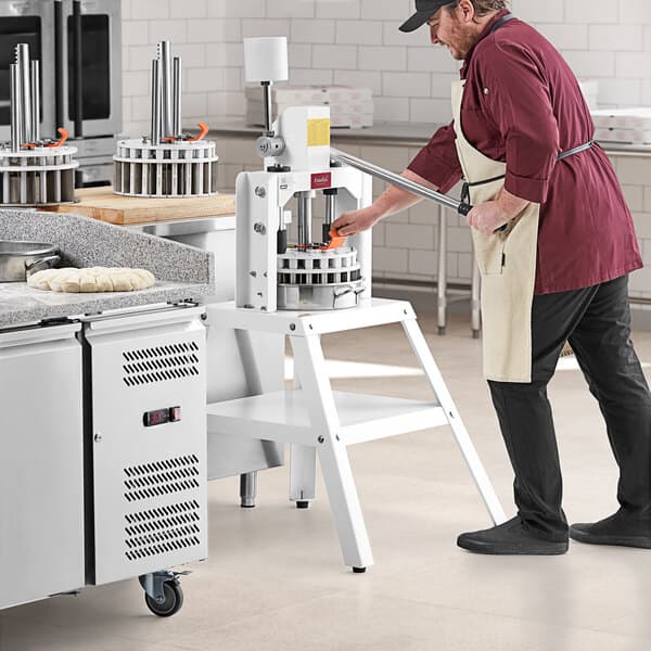 A man in a red shirt and apron using an Estella manual dough divider.