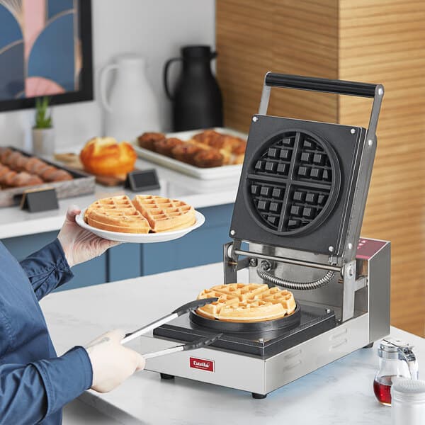 A woman using an Estella Press-Style Belgian Waffle Maker to make waffles.