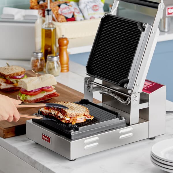 A woman using an Estella panini plate to make a sandwich on a sandwich maker.