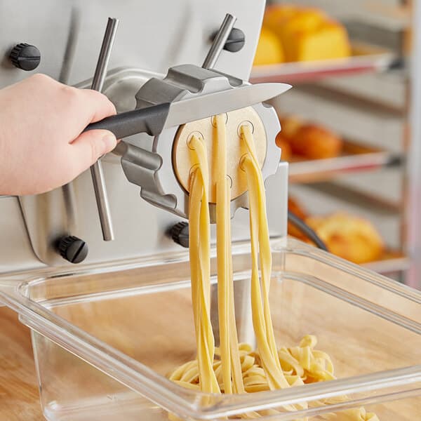 A person using a metal pasta die to cut tagliatelle.