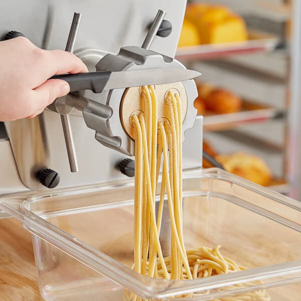 A person using an Estella pasta machine to make bigoli pasta.