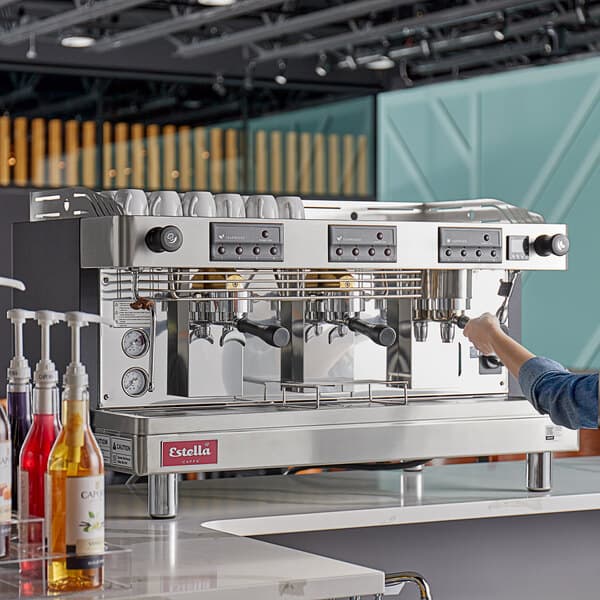 A person using an Estella Caffe Teapresso Machine on a counter in a café.