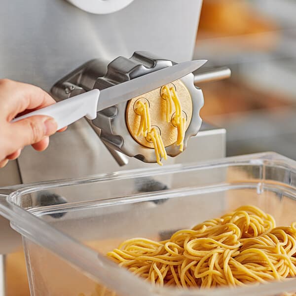 A hand using a knife to cut spaghetti over a bowl.