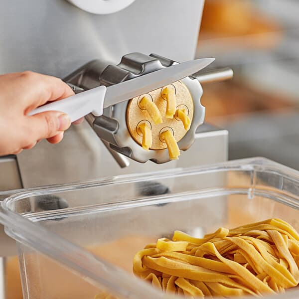 A person using a #34 Tagliatelle pasta die to cut pasta.