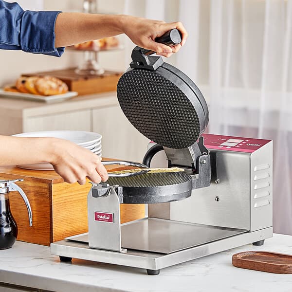 A woman making a waffle cone on an Estella Belgian waffle maker.