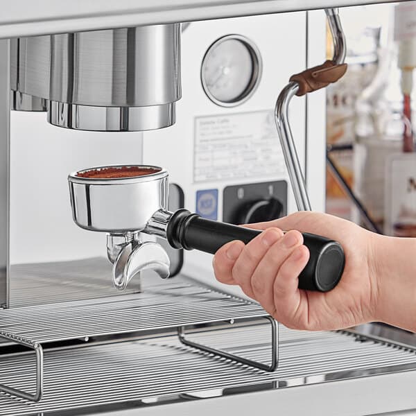 A person holding an Estella Caffe two group automatic espresso machine over a counter.