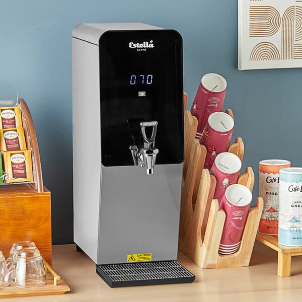 A Estella Caffe digital hot water dispenser with a cup of coffee on top.