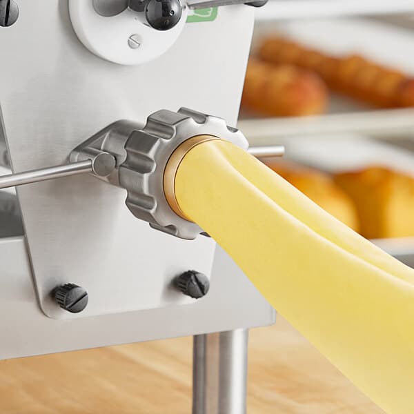 A machine with a yellow Estella lasagna pasta die attached rolling out dough.