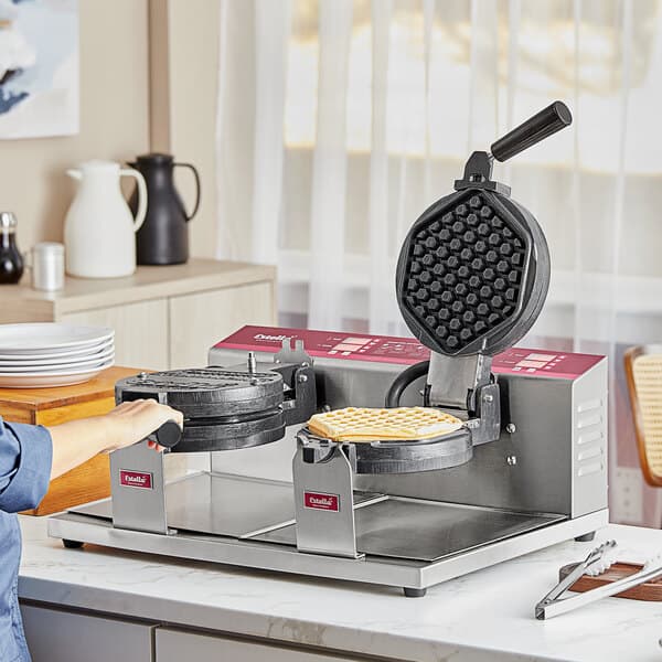 A woman using an Estella Double Belgian Waffle Maker to make waffles.