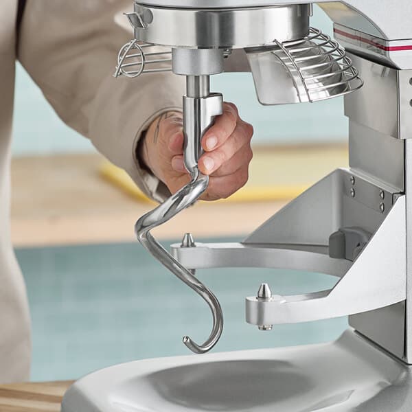 A person holding an Estella metal spiral dough hook.